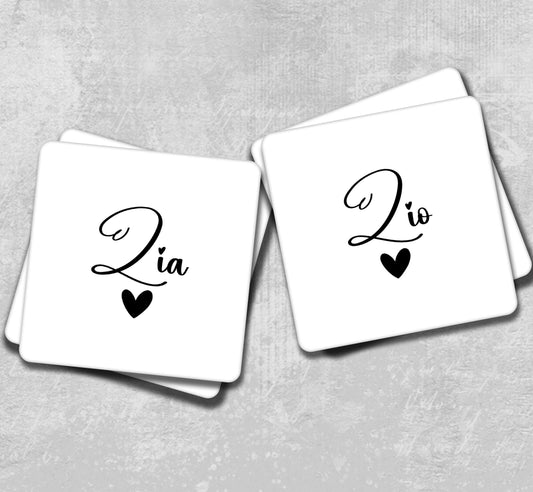 a couple of white coasters with black hearts on them