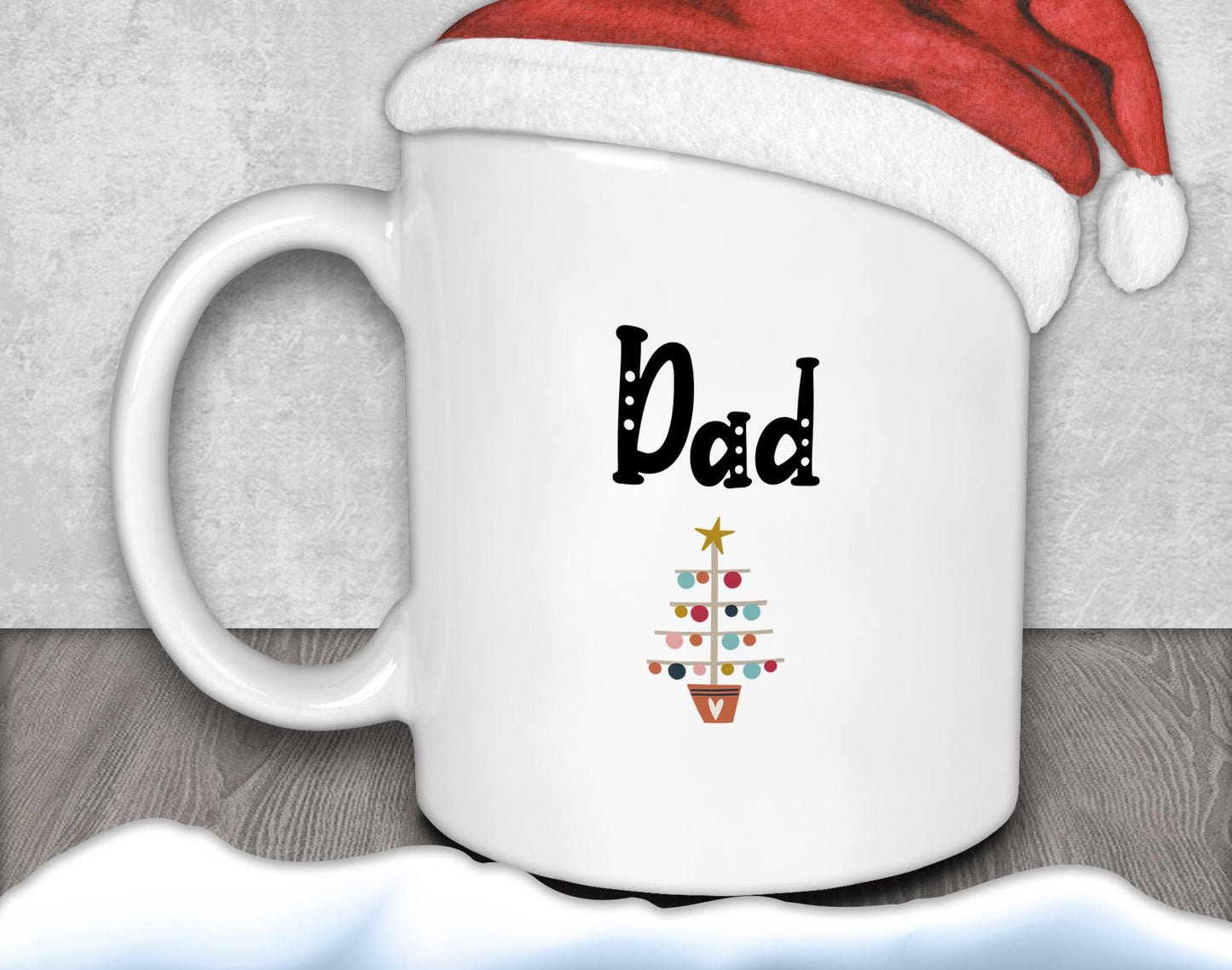 A white mug with a red Santa hat on top, and a Christmas tree design on the mug.