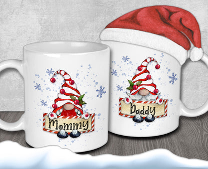two white mugs with Christmas-themed designs, including gnomes and snowflakes. One mug has a Santa hat on it, and the other mug has a sign that says &quot;Mommy&quot; and &quot;Daddy&quot;.