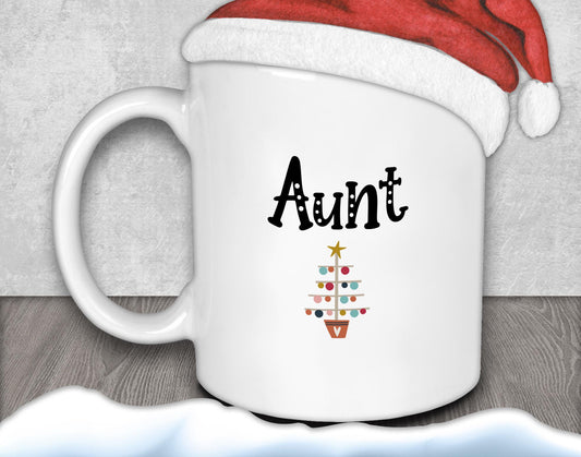 A white mug with the word "Aunt" printed on it, along with a Christmas tree design.