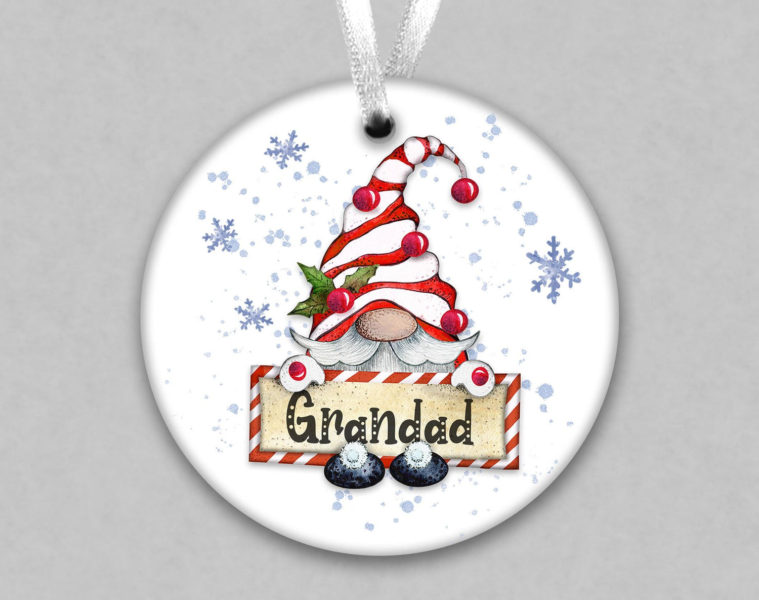 A white ornament with a red and white striped hat, snowflakes, and a sign that says "Grainad".