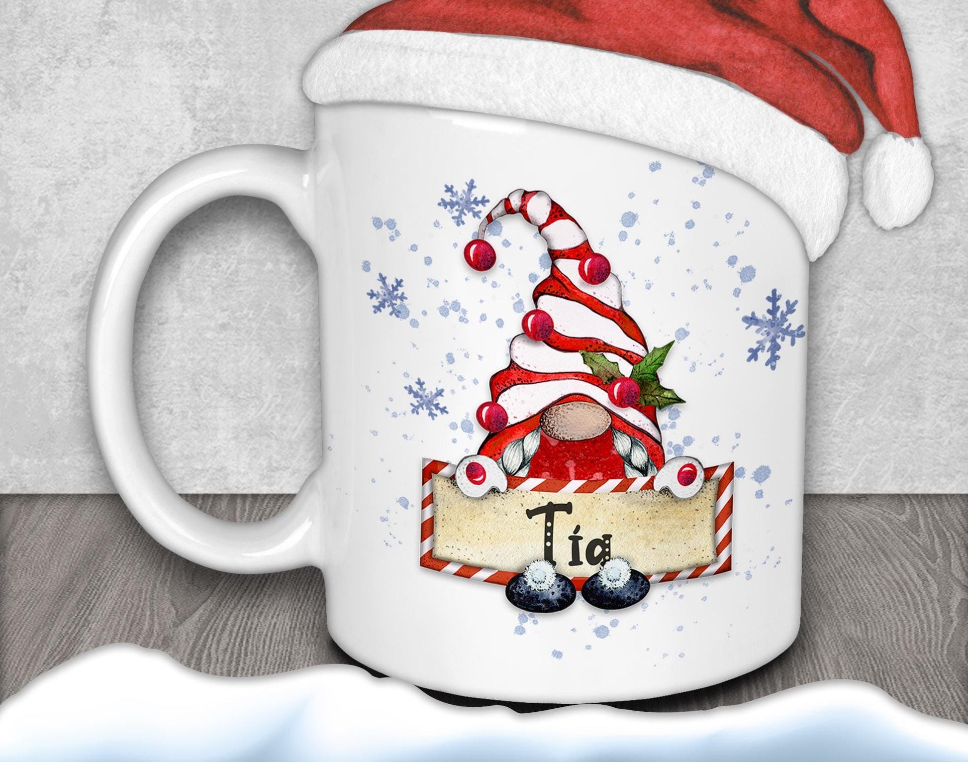 A white mug with a Christmas-themed design featuring a gnome wearing a Santa hat and holding a sign with the word &quot;Tie&quot; written on it.