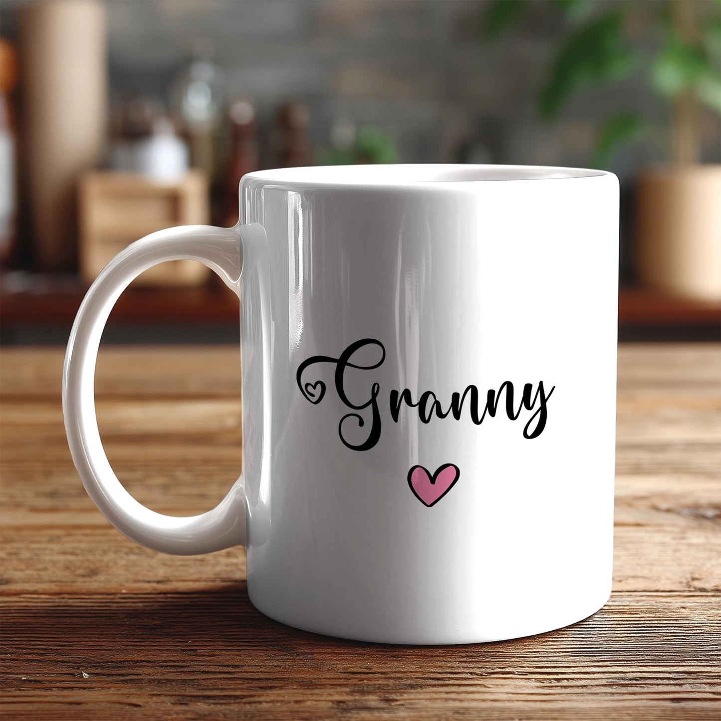 A white ceramic mug with the word "Granny" and a heart symbol printed on it, placed on a wooden surface.