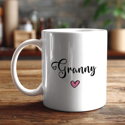 A white ceramic mug with the word "Granny" and a heart symbol printed on it, placed on a wooden surface.