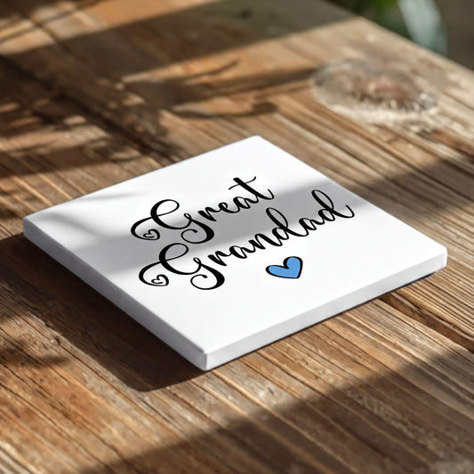 A white square coaster with the text "Great Grandad" and a blue heart symbol on it, placed on a wooden surface.