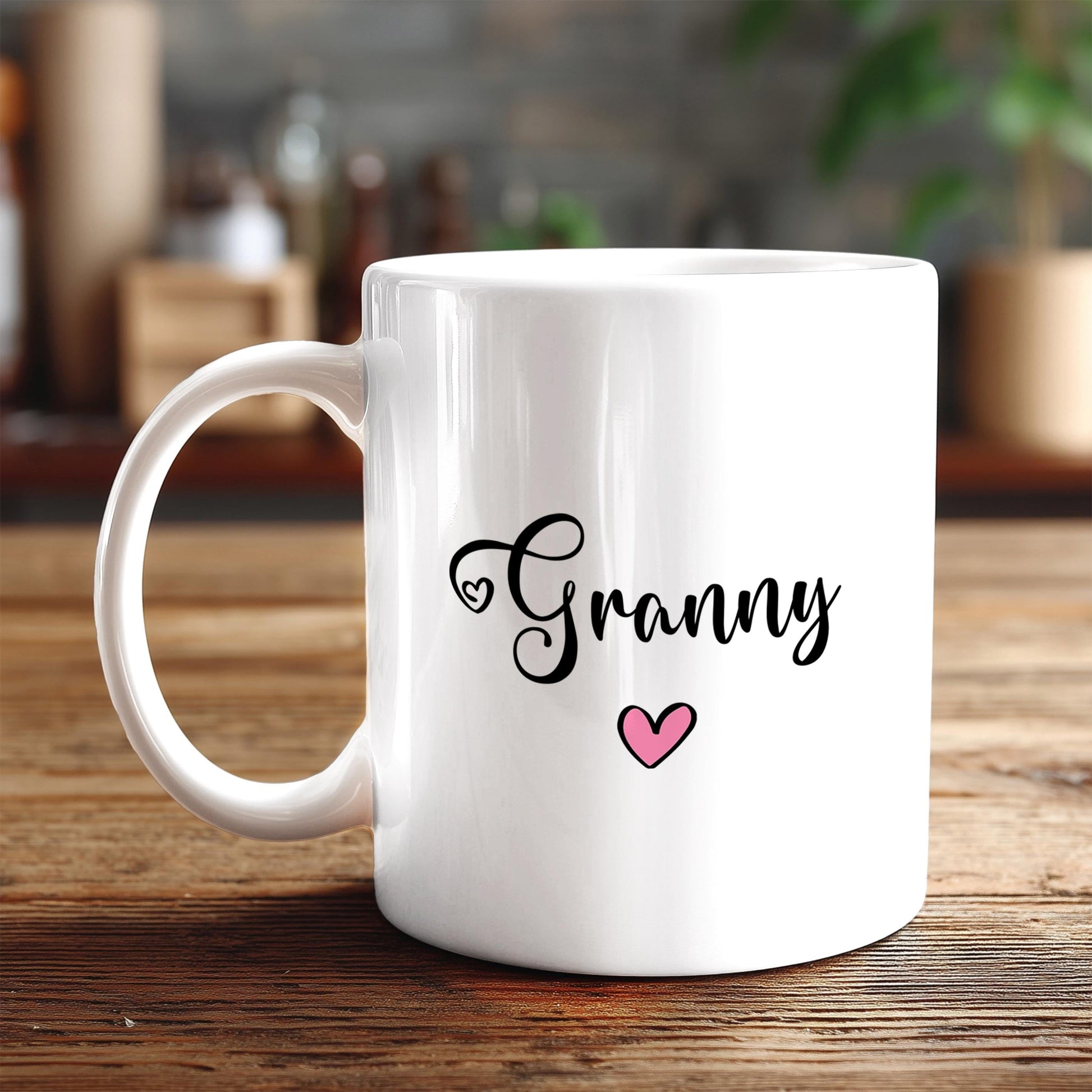 A white ceramic mug with the word "Granny" written on it, along with a heart symbol, sits on a wooden surface.