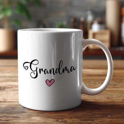 A white ceramic mug with the text "Grandma" and a heart symbol printed on it, placed on a wooden surface.