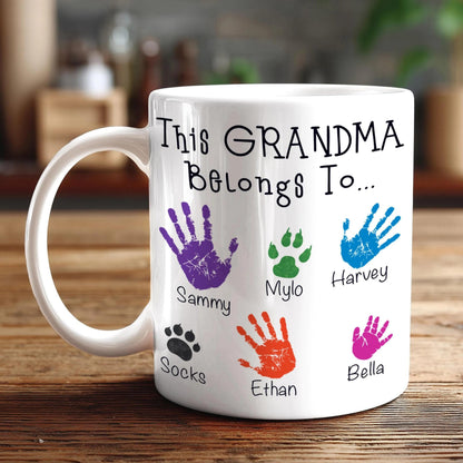 A white mug with a personalized message and handprints of the names of the people it belongs to.
