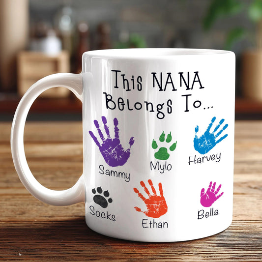 A white mug with a personalized message and handprint designs on it.