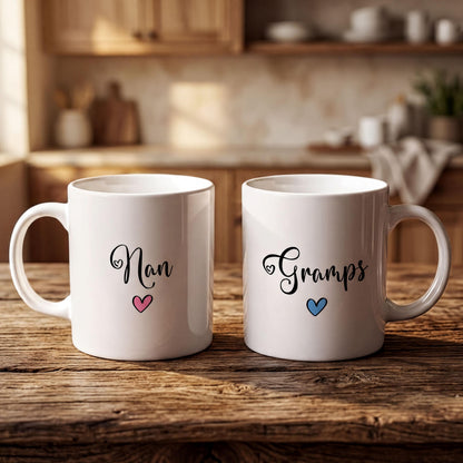 Two white mugs with personalized names and hearts on them, placed on a wooden surface.