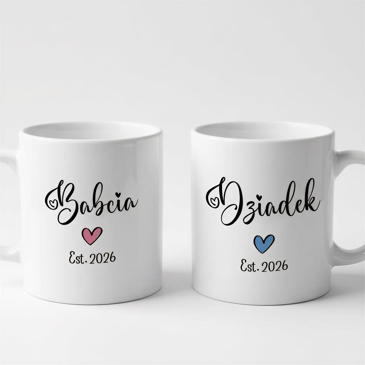 Two white ceramic mugs with black text and heart designs.