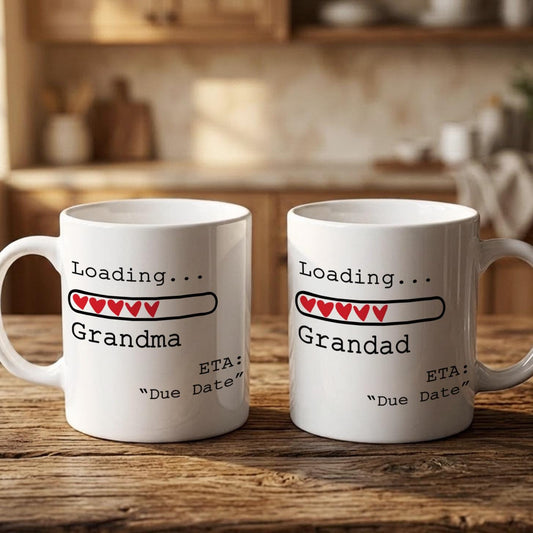 Two white mugs with text and graphics on them, placed on a wooden surface.