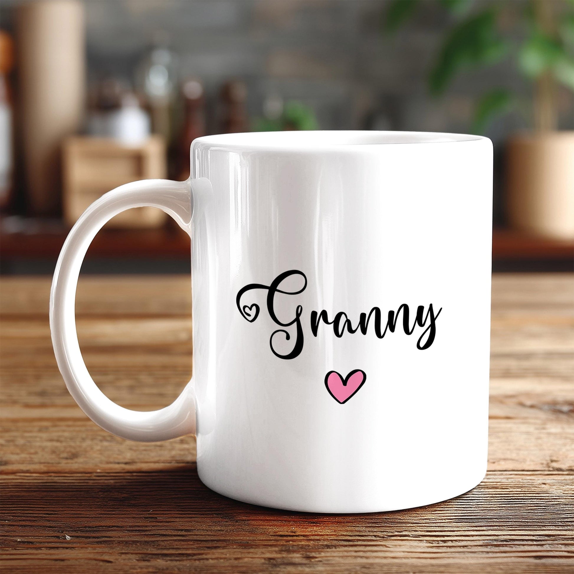 A white ceramic mug with the word "Granny" written on it, along with a heart symbol, sits on a wooden surface.