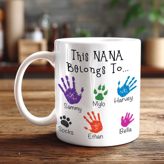 A white mug with a personalized message and handprint designs on it.