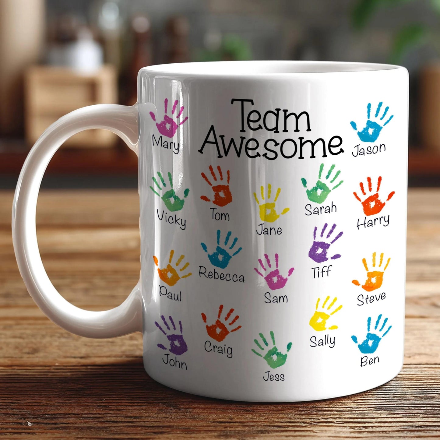 A white coffee mug with colorful handprints and the text "Team Awesome" printed on it.
