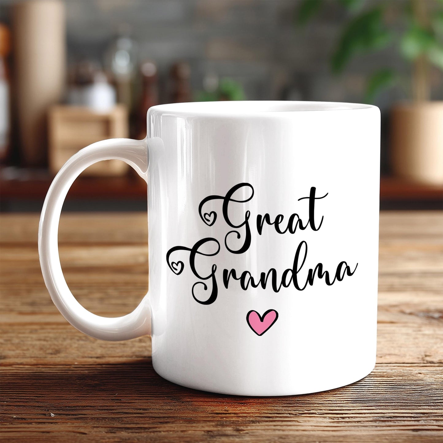 A white ceramic mug with the text "Great Grandma" and a pink heart printed on it, placed on a wooden surface.