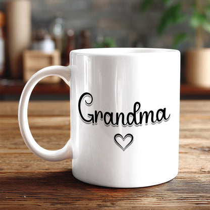 A white ceramic mug with the word "Grandma" and a heart symbol printed on it, placed on a wooden surface.