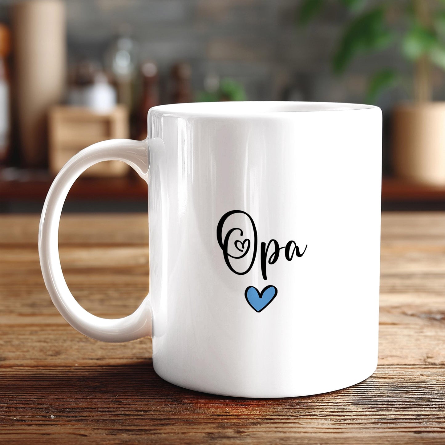 A white ceramic mug with the text "Opa" and a blue heart symbol printed on it, placed on a wooden surface.