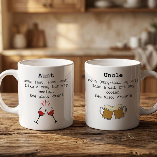 Two white mugs with humorous text and illustrations on them, placed on a wooden surface.