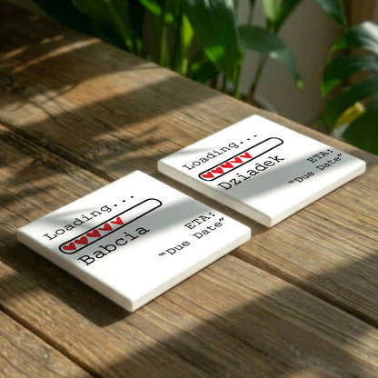 two white square coasters with a loading bar graphic and text, placed on a wooden surface.