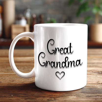 A white ceramic mug with the text "Great Grandma" printed on it, along with a heart symbol, sits on a wooden surface.