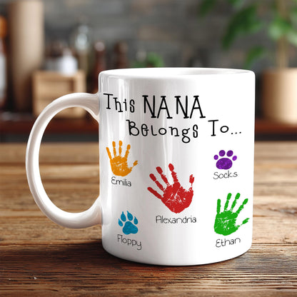 A white mug with a personalized message and handprints of different people's names and paw prints.