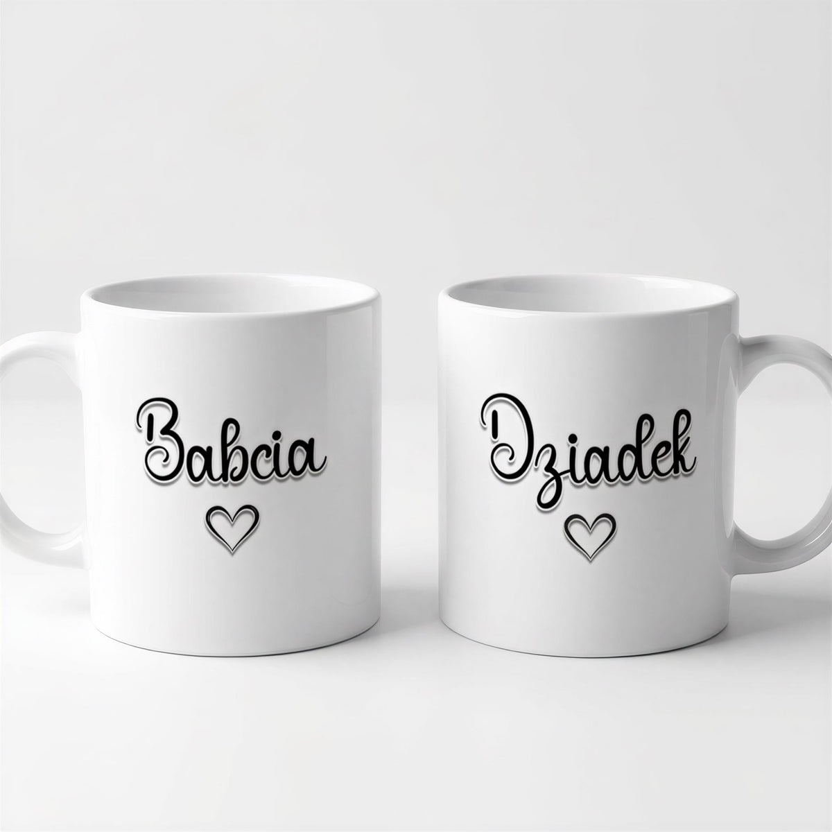 Two white ceramic mugs with black text and heart symbols on them.
