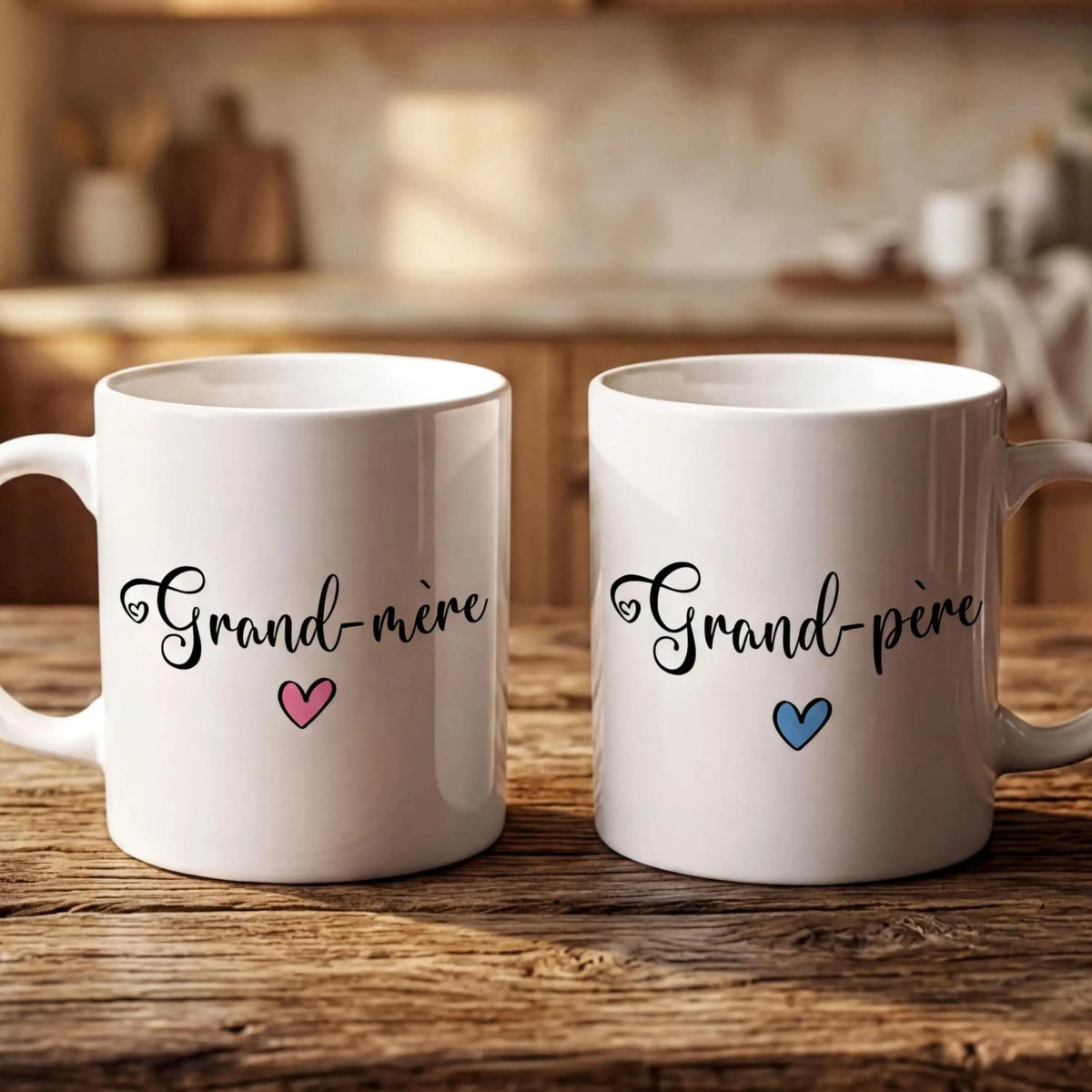 Two white mugs with the text "Grand-more" and "Grand-pire" printed on them, placed on a wooden surface.