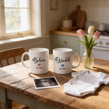 two white mugs with personalized names and a baby onesie on a wooden table, along with a vase of pink tulips and an ultrasound image.
