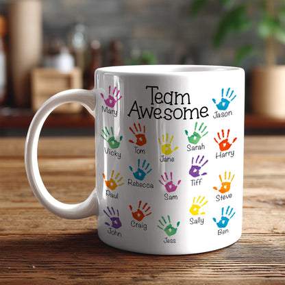 A white ceramic mug with colorful handprints on it, each containing a name.