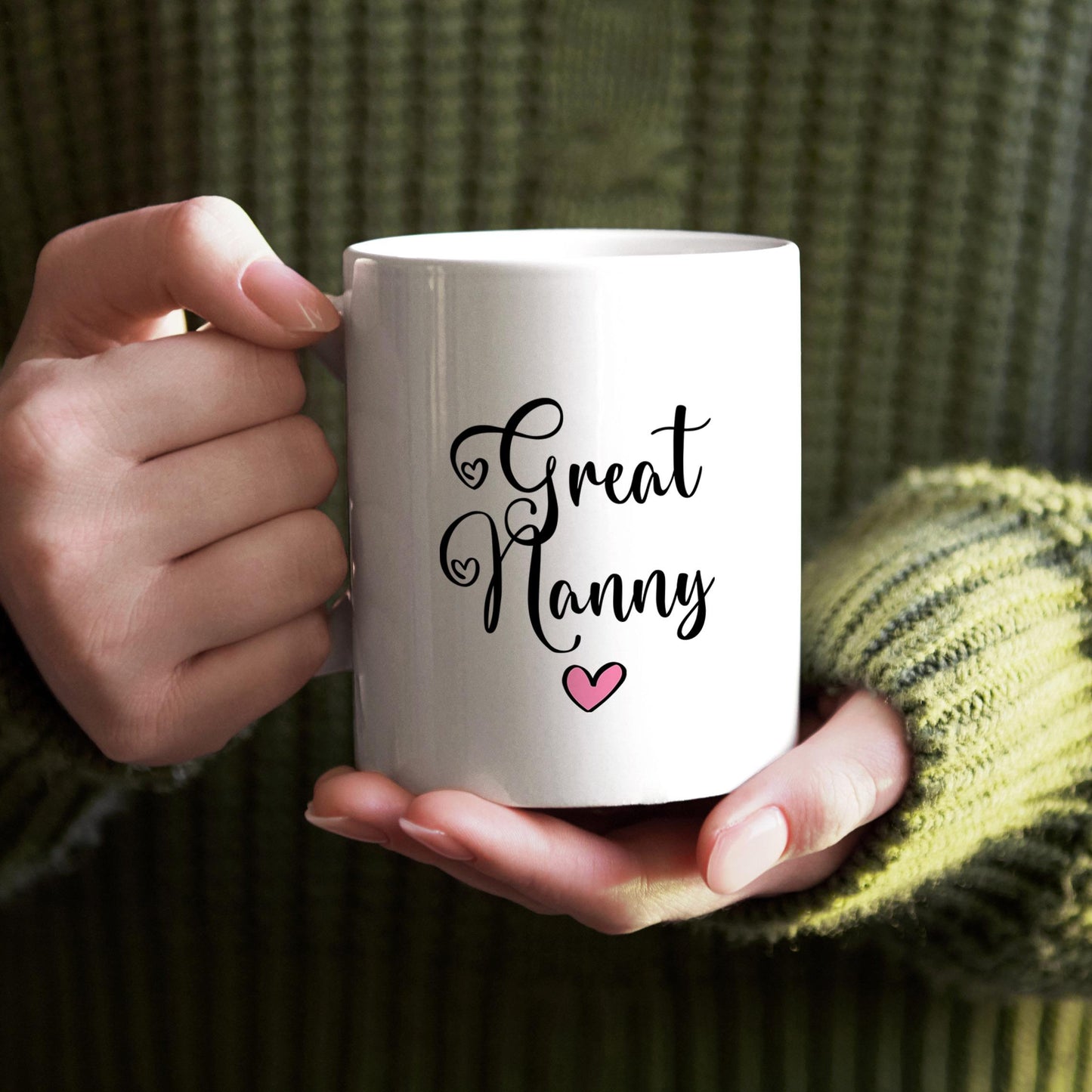 A person's hands holding a white mug with the text "Great Nanny" and a heart symbol printed on it.