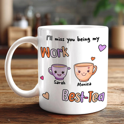 A white coffee mug with a personalized message and illustrations of two cartoon characters, one being Sarah and the other Monica, along with the text "I'll miss you being my Work Best-Tea".