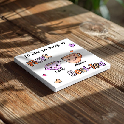 A white square coaster with a message about missing someone and a cartoon image of two cups of tea.
