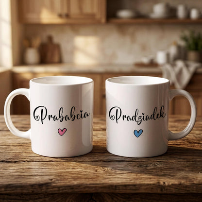 Two white mugs with the Polish phrase "Prabciacia" and a heart symbol printed on them, placed on a wooden surface in a kitchen setting.