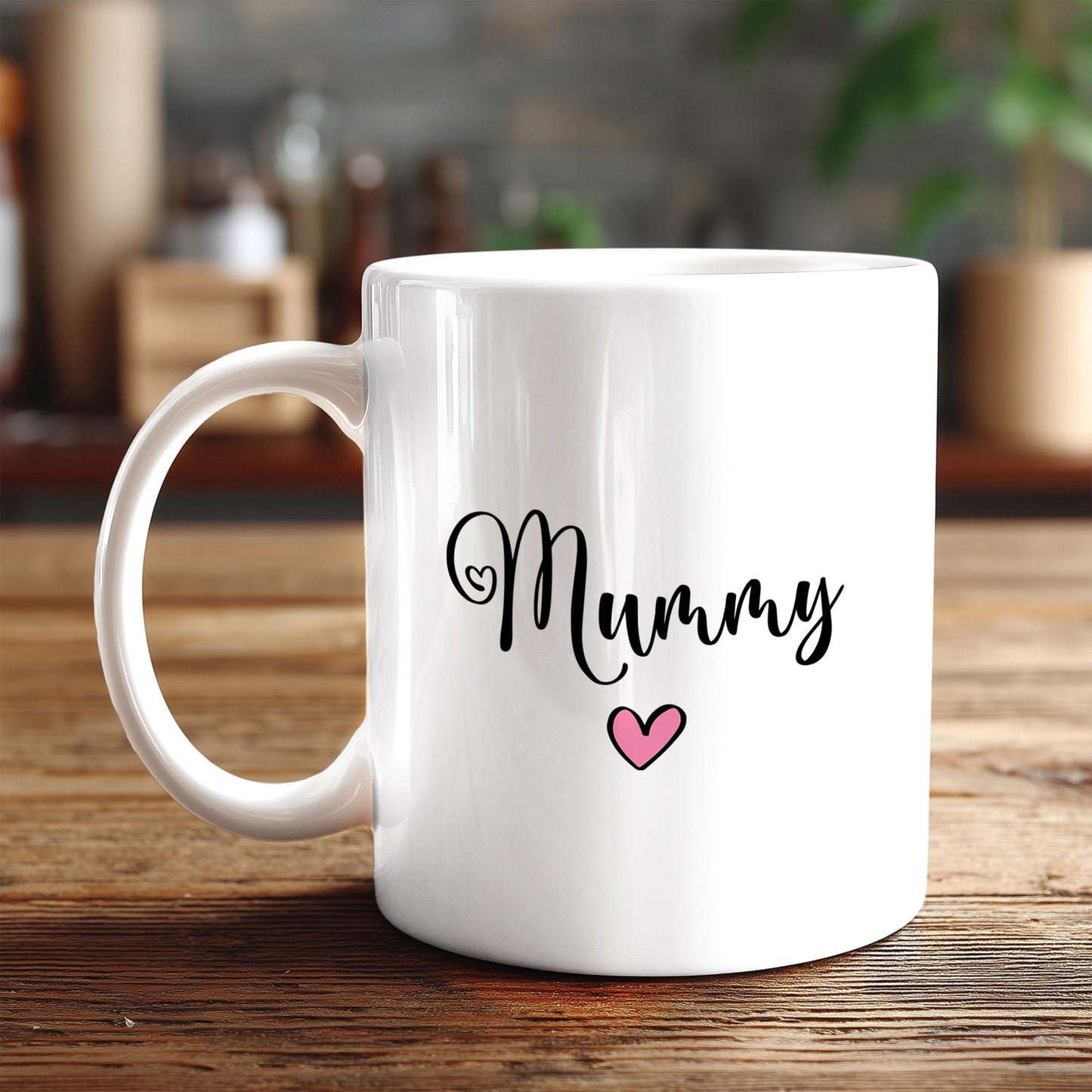 A white ceramic mug with the word "Mummy" written on it, along with a pink heart symbol, sits on a wooden surface.