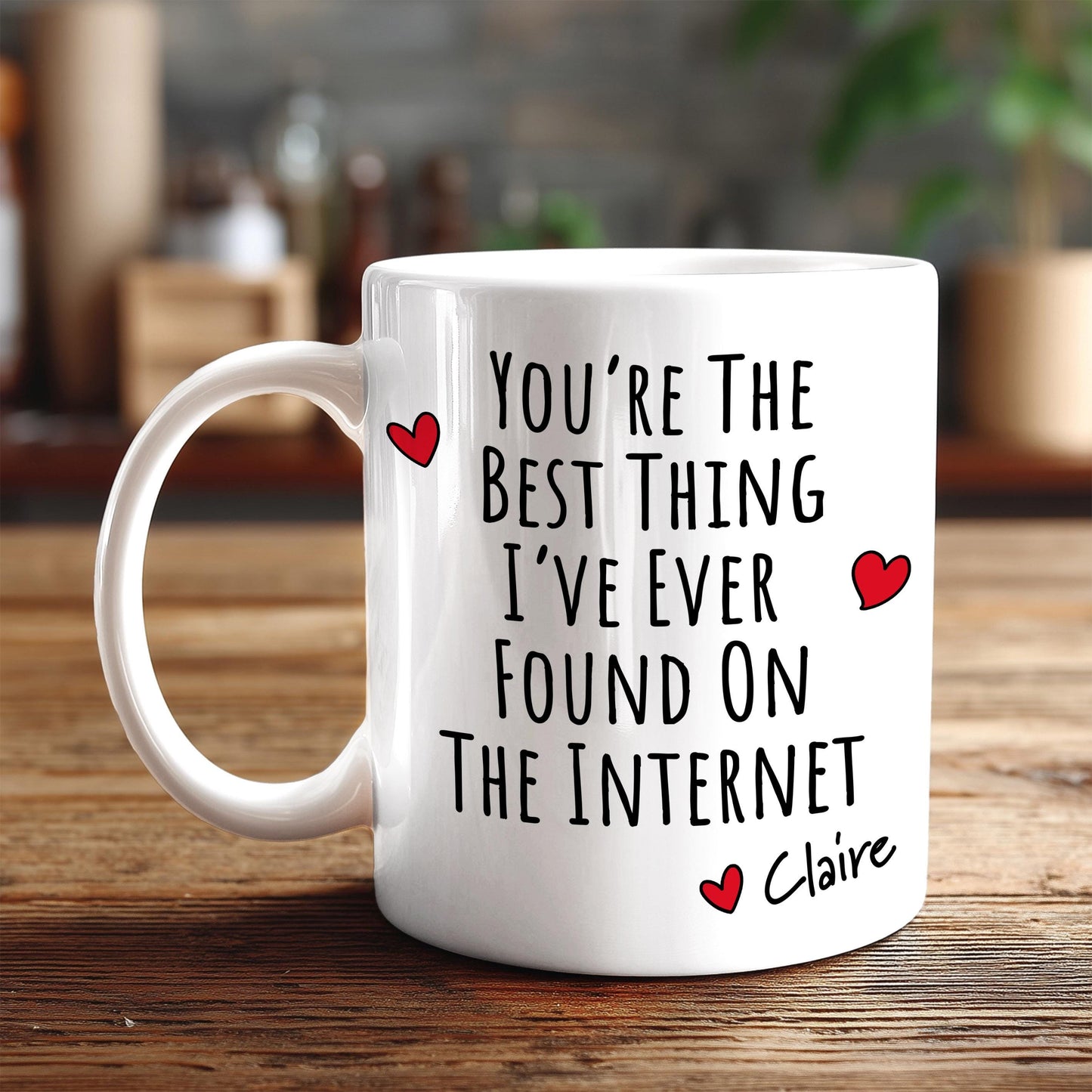 A white coffee mug with text printed on it, sitting on a wooden surface.