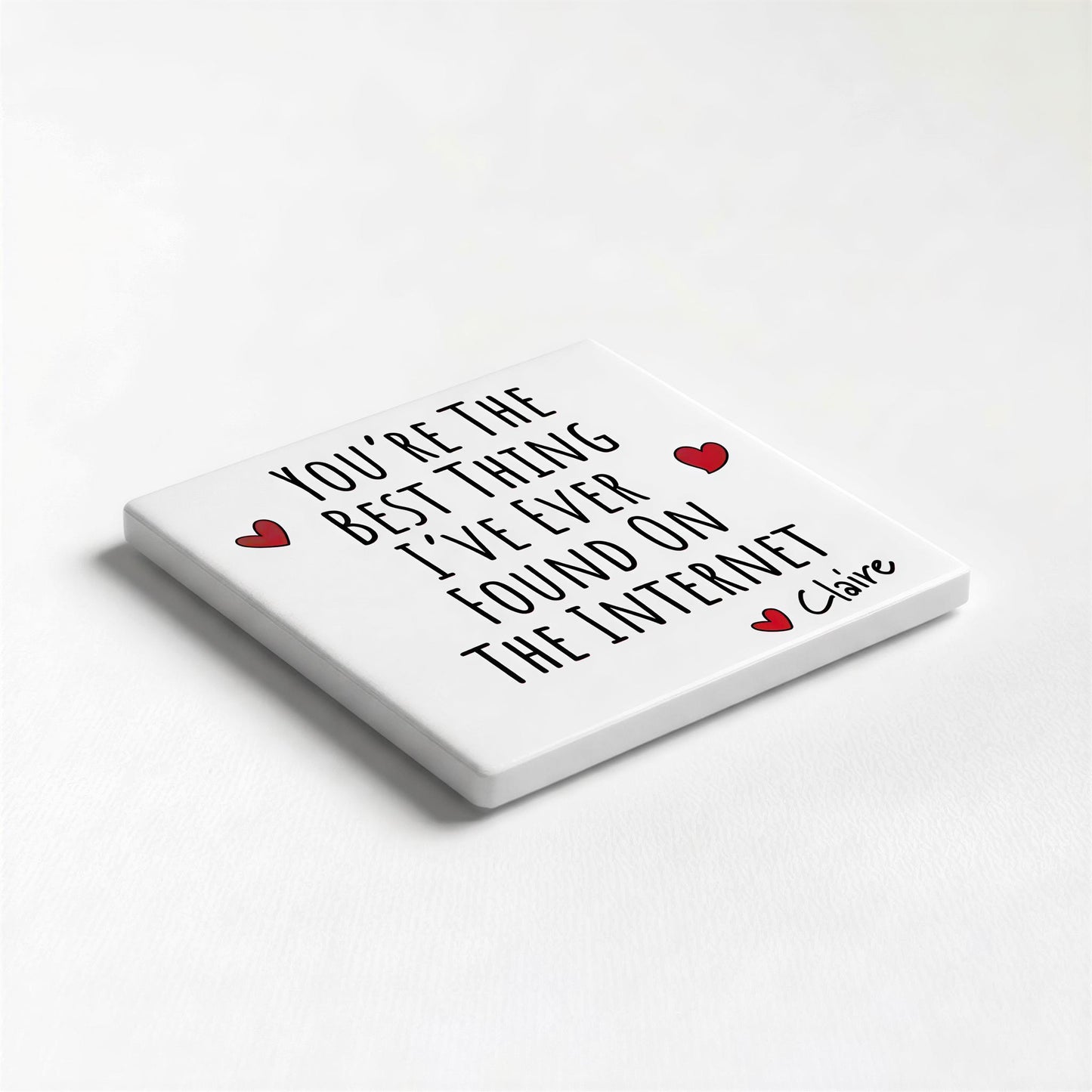 A white square coaster with black text and two red heart symbols.