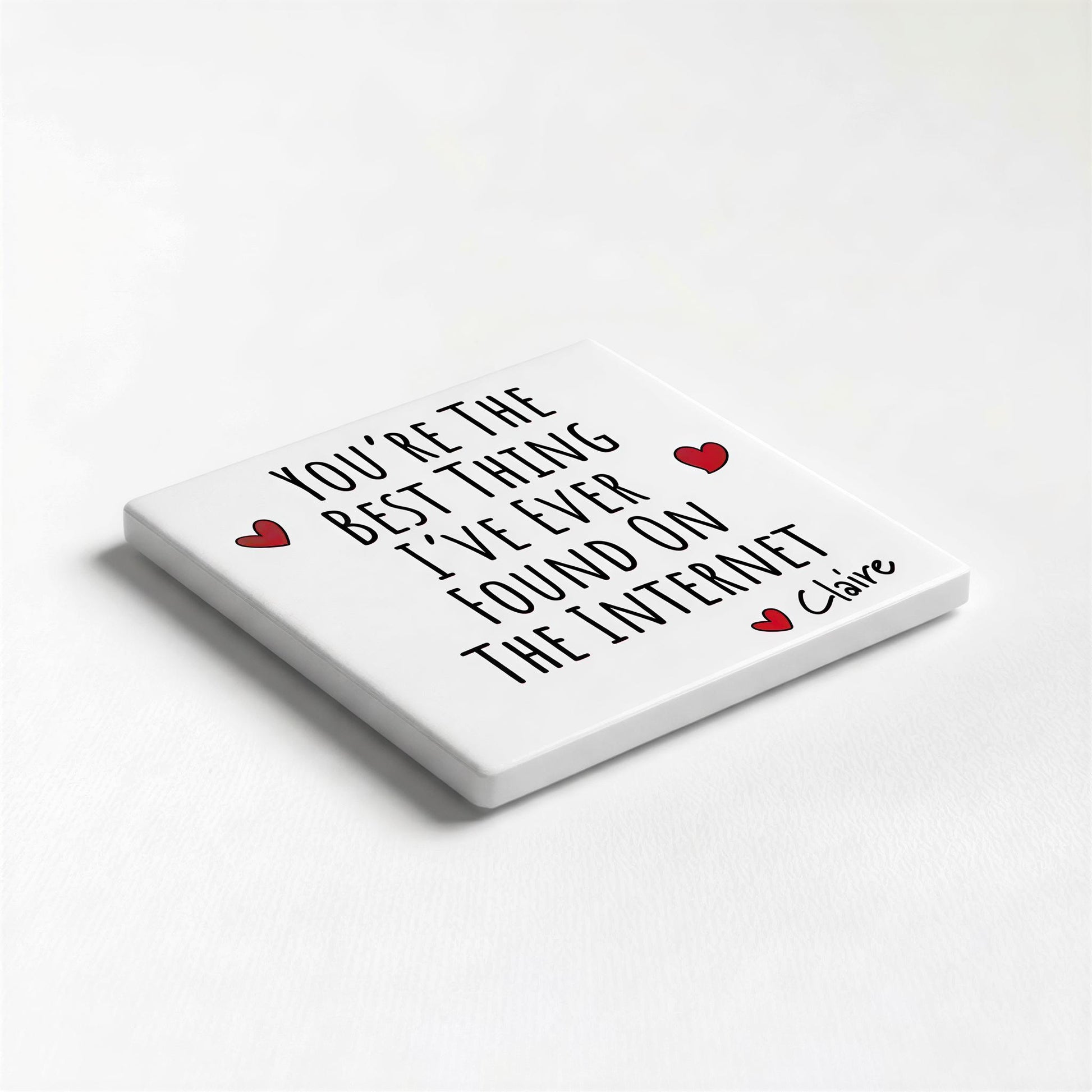 A white square coaster with black text and two red heart symbols.