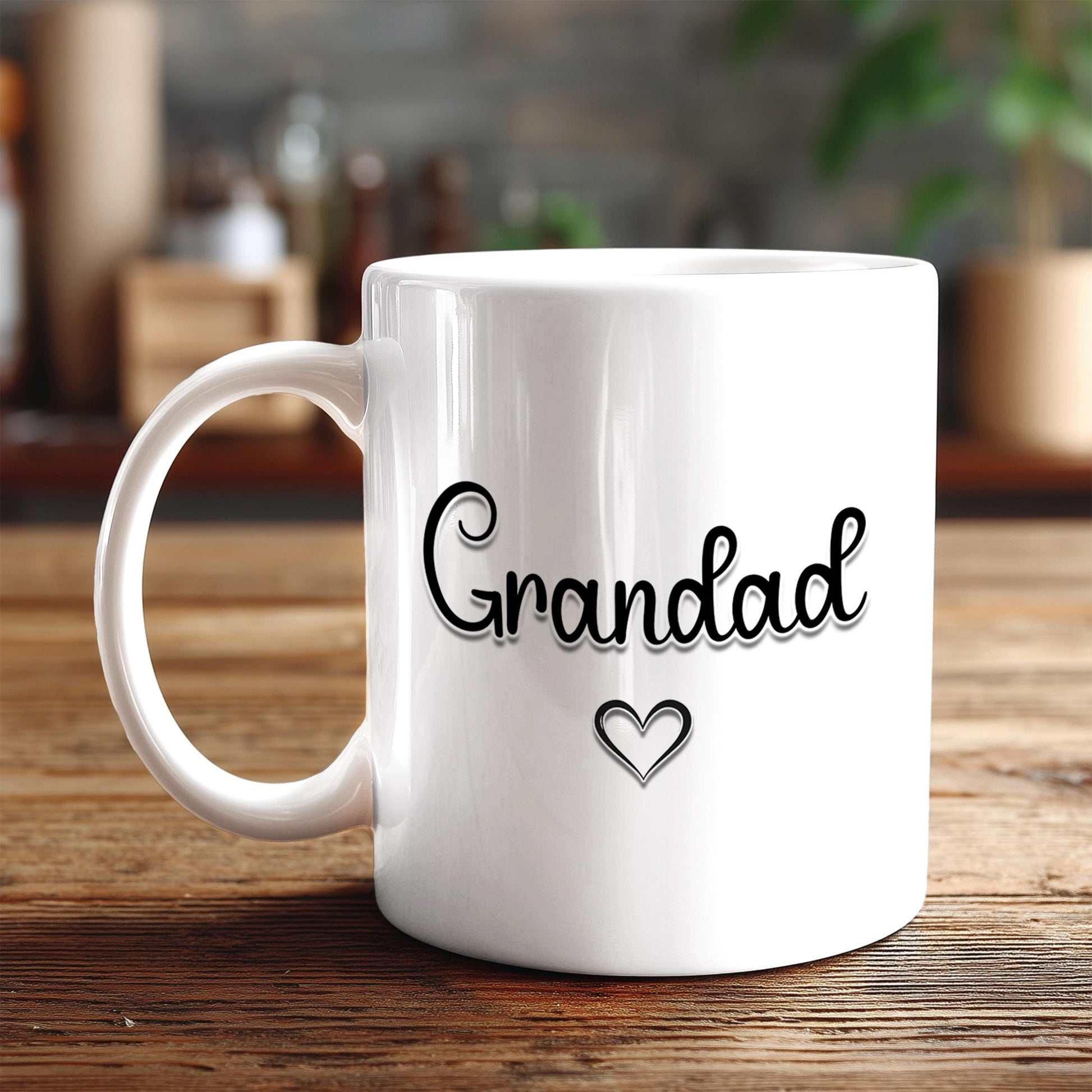 A white ceramic mug with the text "Grandad" and a heart symbol printed on it, placed on a wooden surface.