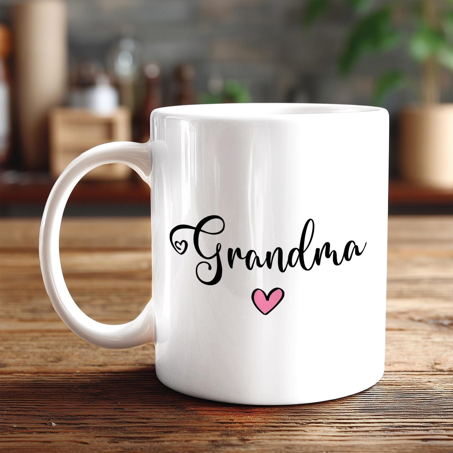 A white ceramic mug with the text "Grandma" and a heart symbol printed on it, placed on a wooden surface.