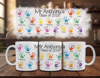 three white mugs with colorful handprint designs and text, likely representing the names of students in a class of 2026.