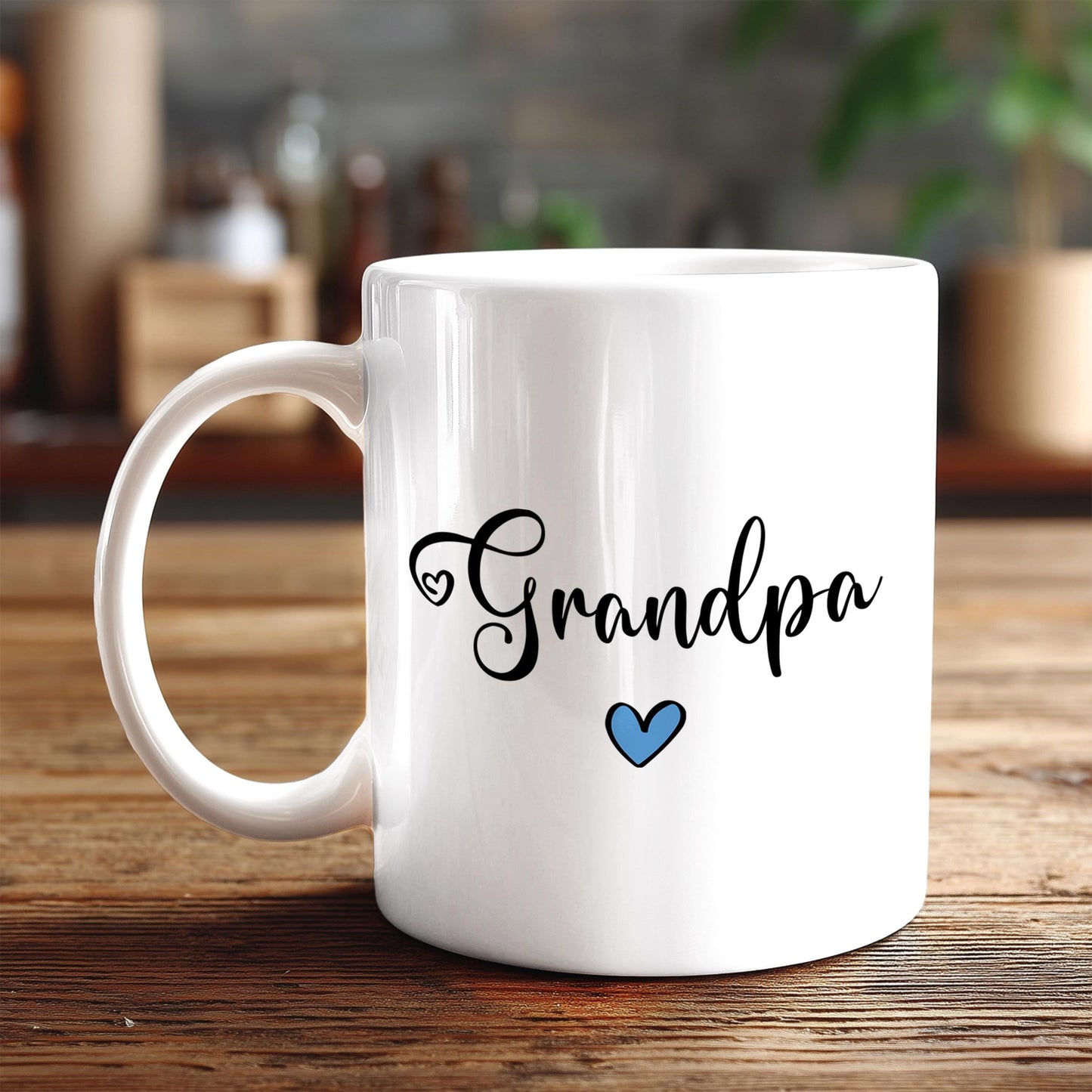 A white ceramic mug with the text "Grandpa" and a blue heart symbol printed on it, placed on a wooden surface.