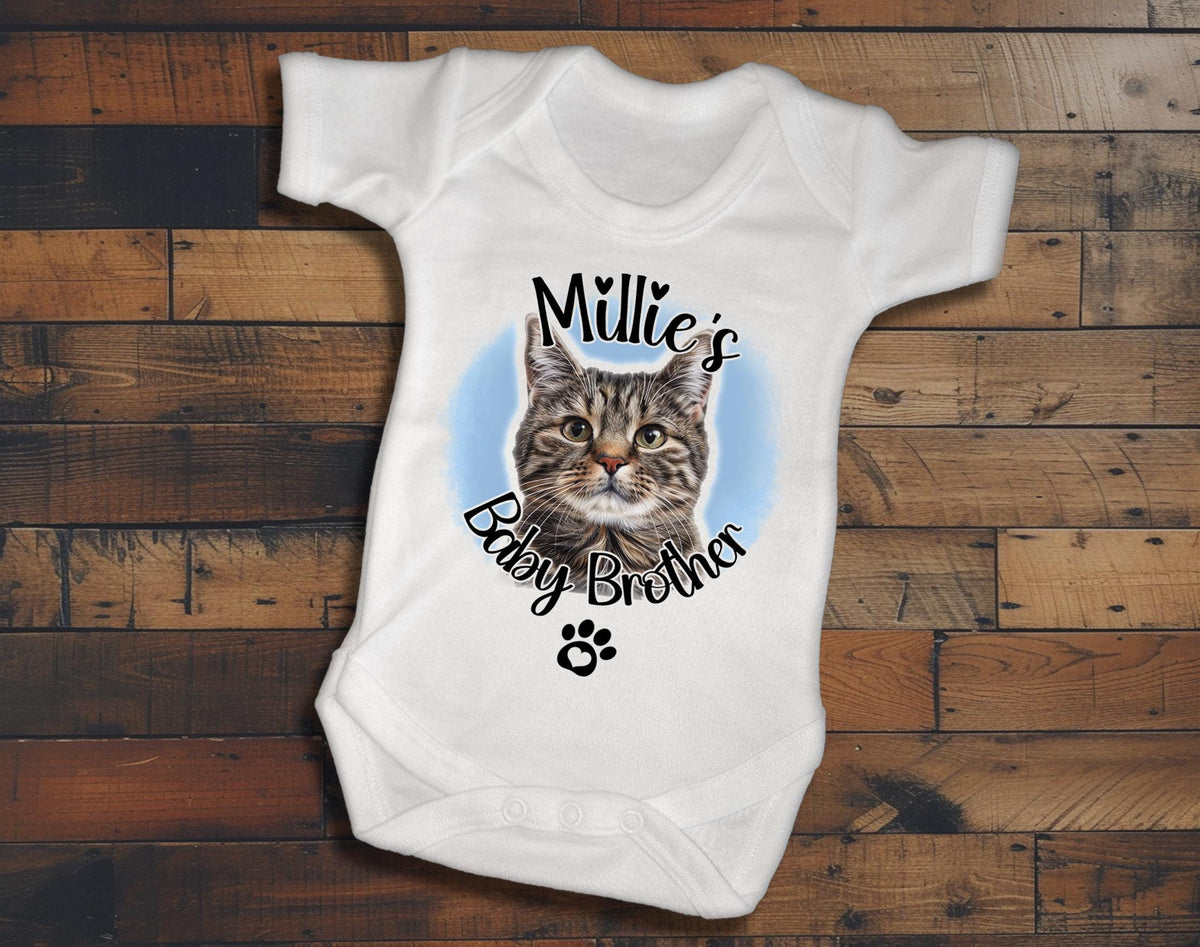 A white baby onesie with a cat image and the text "Milly's Baby Brother" printed on it.