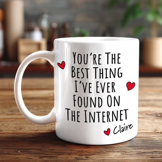 A white coffee mug with text printed on it, sitting on a wooden surface.