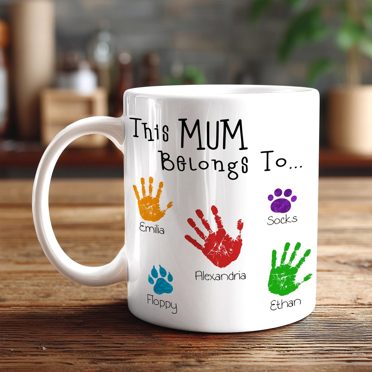 A white mug with handprint designs and names printed on it.
