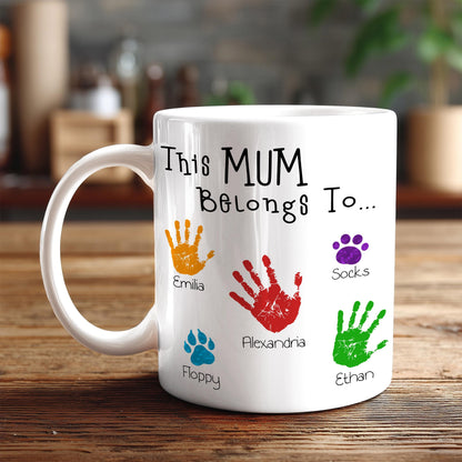 A white mug with handprint designs and names printed on it.