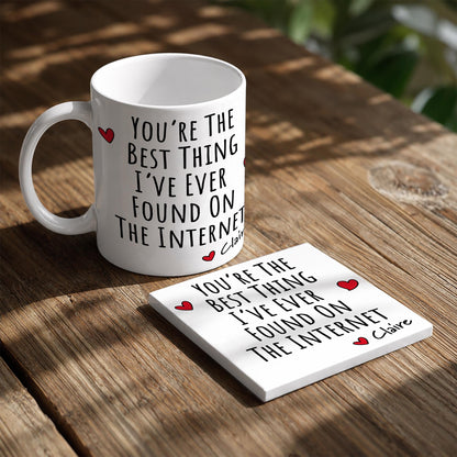 A white mug with a humorous message printed on it, sitting on a wooden table next to a coaster with a similar message.
