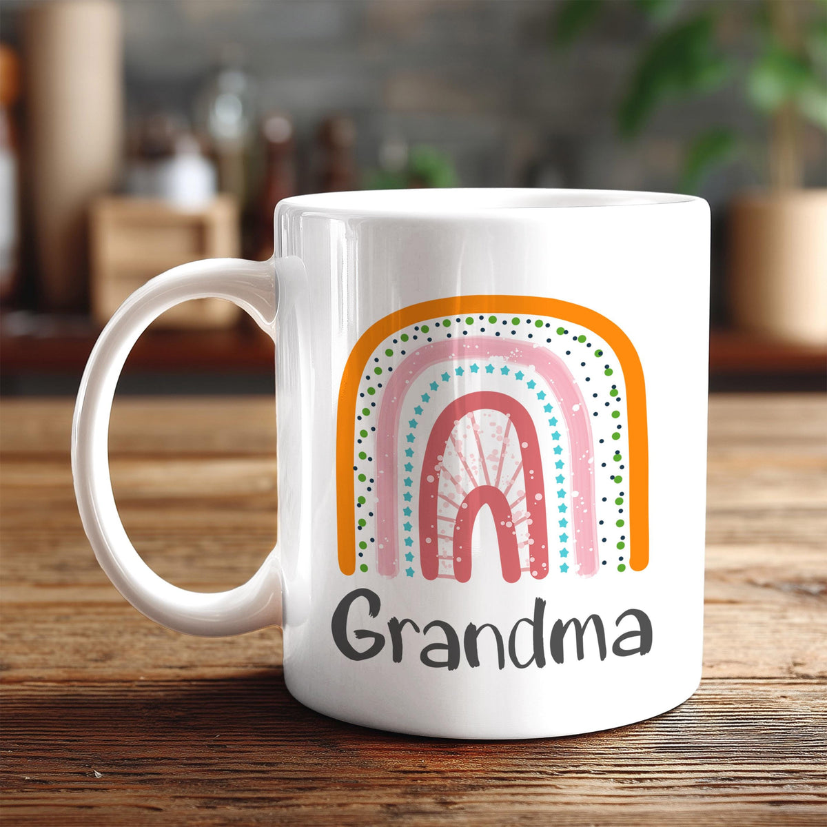 A white ceramic mug with a colorful rainbow design and the word "Grandma" printed on it, placed on a wooden surface.
