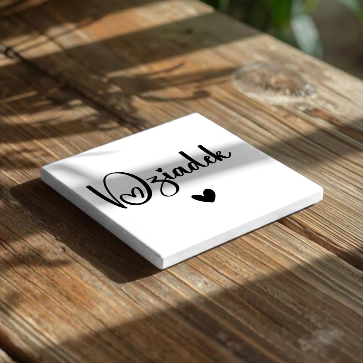 A white square with black text and a heart symbol is placed on a wooden surface.