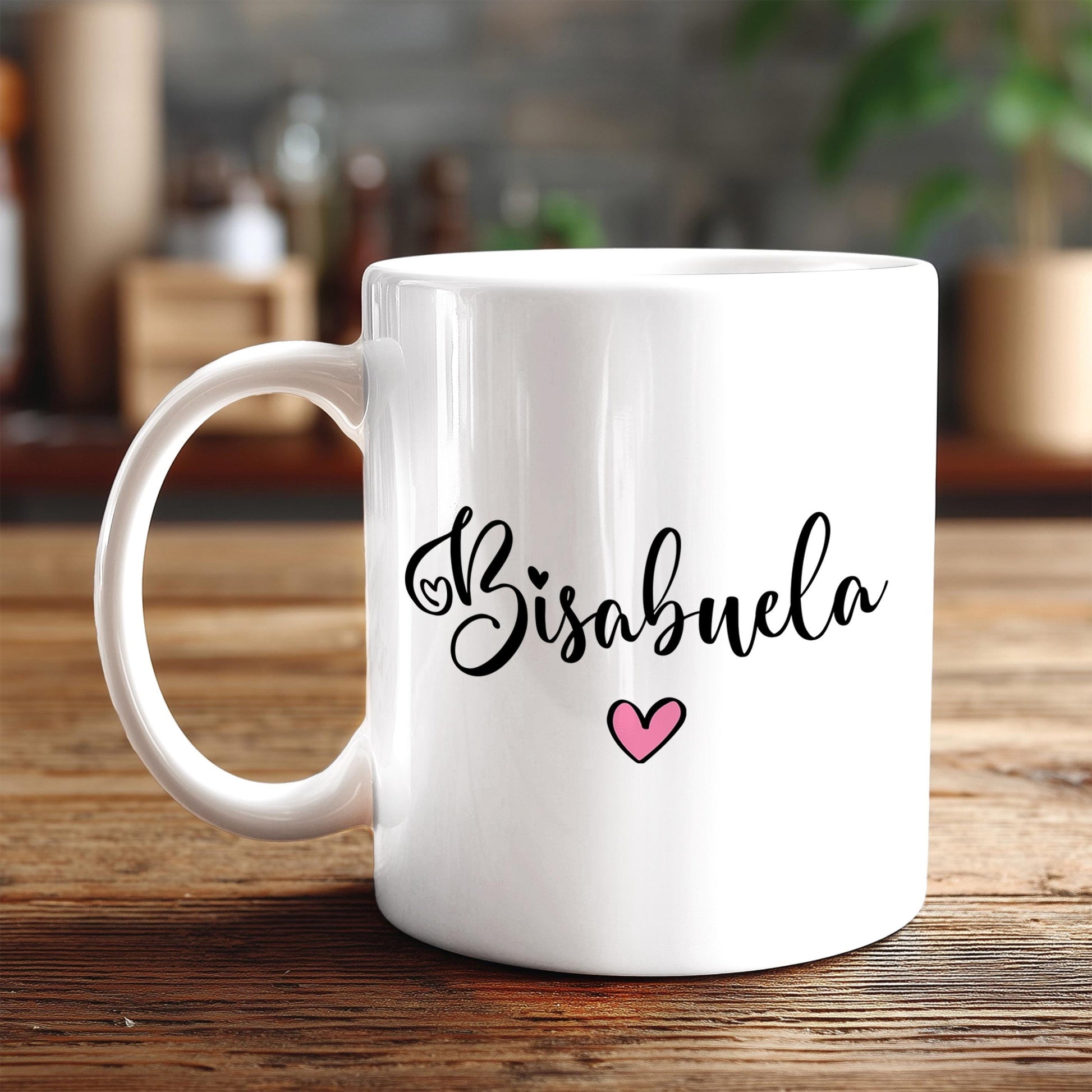 A white ceramic mug with the text "Bisabuela" and a pink heart printed on it, placed on a wooden surface.